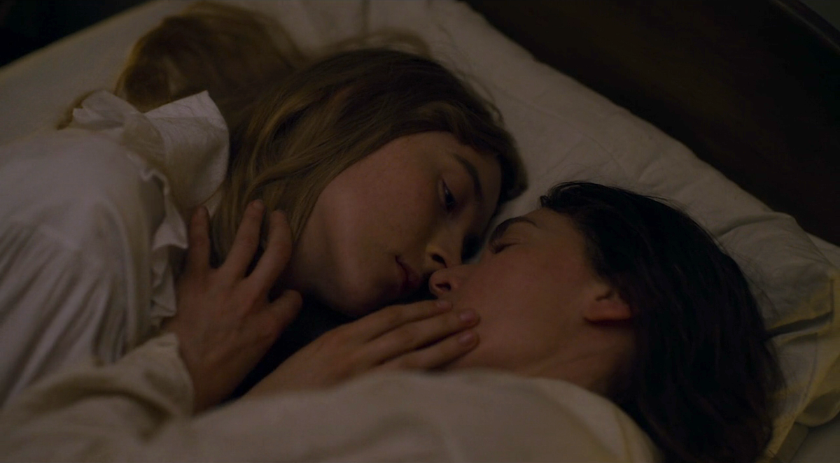 Saoirse Ronan and Kate Winslet caress each other's faces in bed.