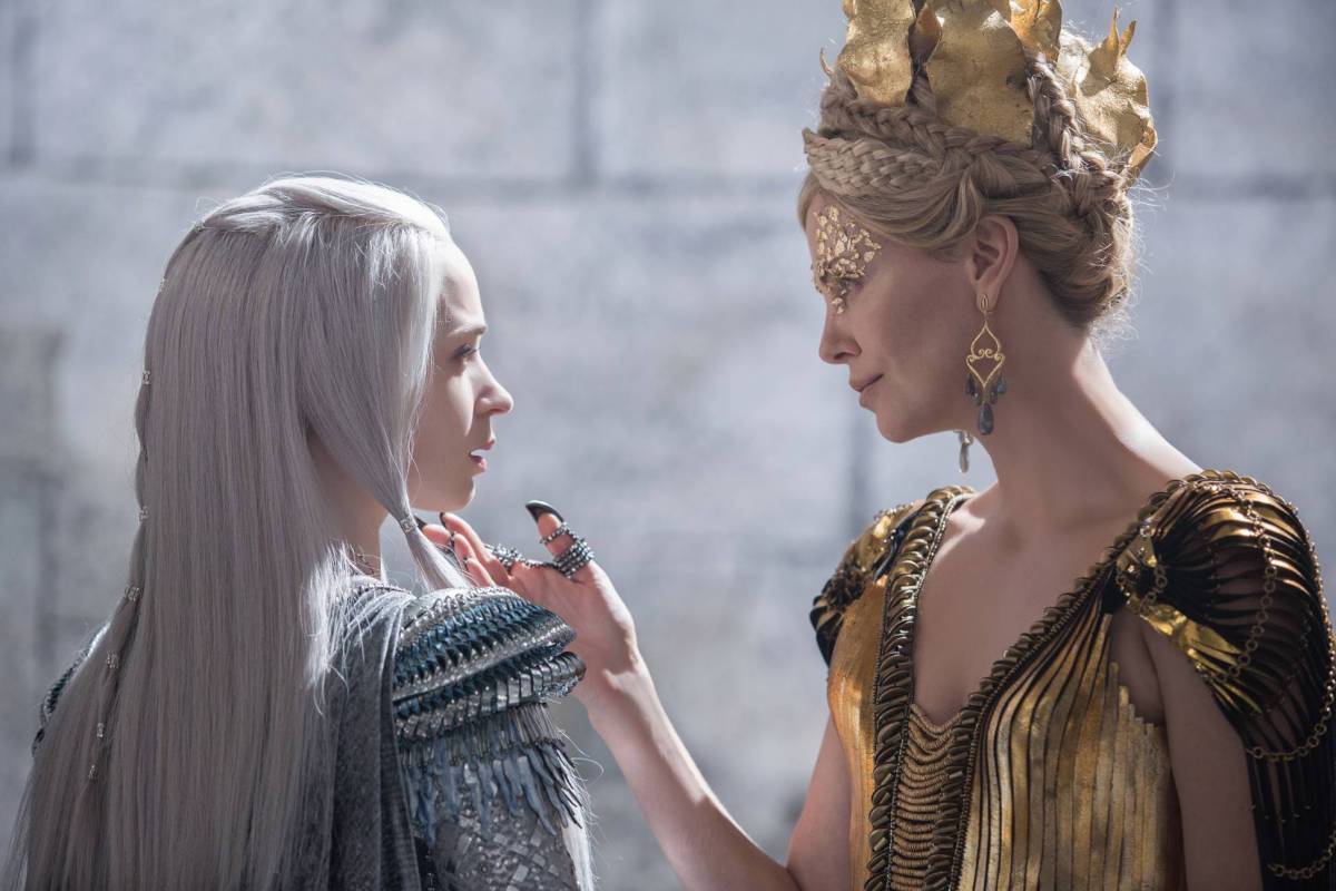 Still from The Huntsman. Charlize Theron as the evil queen strokes Emily Blunt's chin.