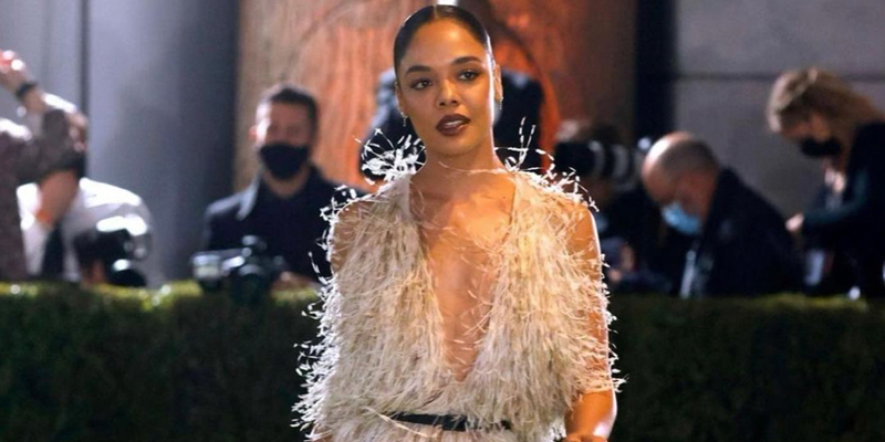 Tessa Thompson walks a runway in a dress with a lot of tassels on it