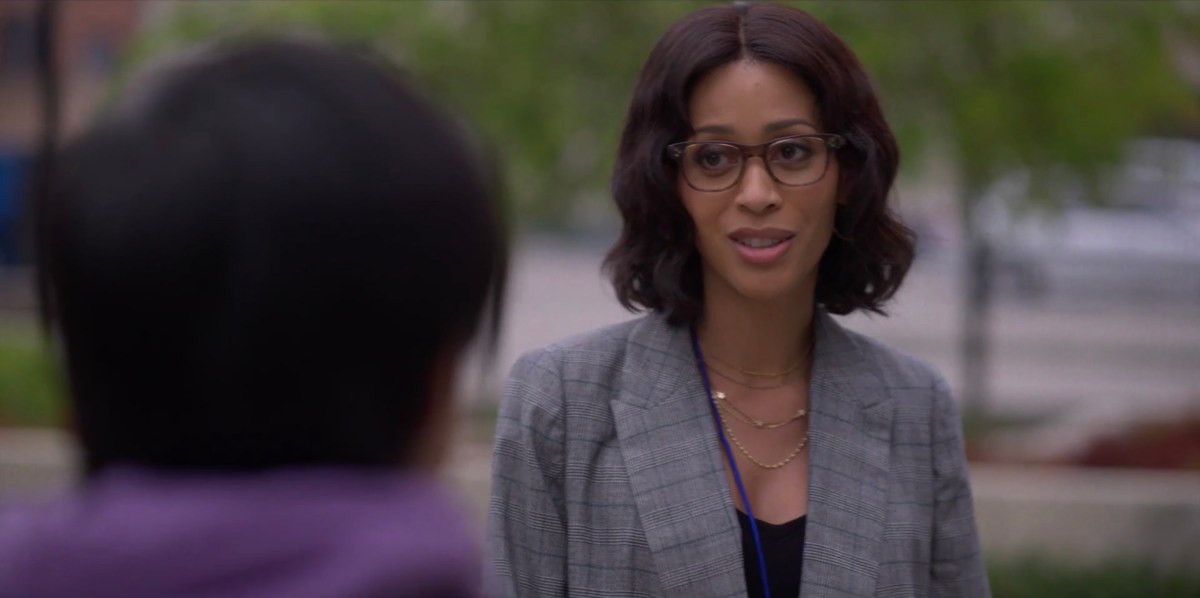 Claudia in a grey blazer outside the LGBT Center, talking to Micah