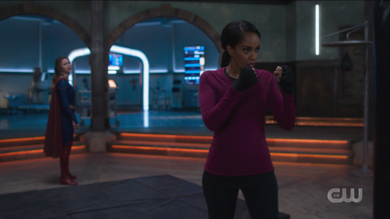 Kelly gets ready to punch a punching bag while Supergirl asks to join