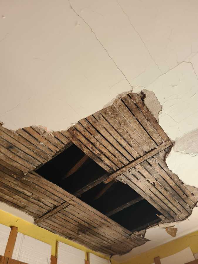 This hole is much larger than the others. It is huge. There is a massive amount of plaster missing and a very large hole torn out of the lath. Behind the lath, there's darkness after two beams.