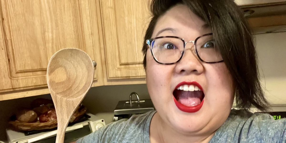 photo of author in her kitchen holding a spoon