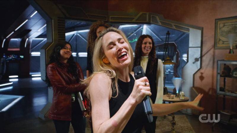 Sara wails into the karaoke mike while Human Gideon, Spooner and Astra laugh in the background