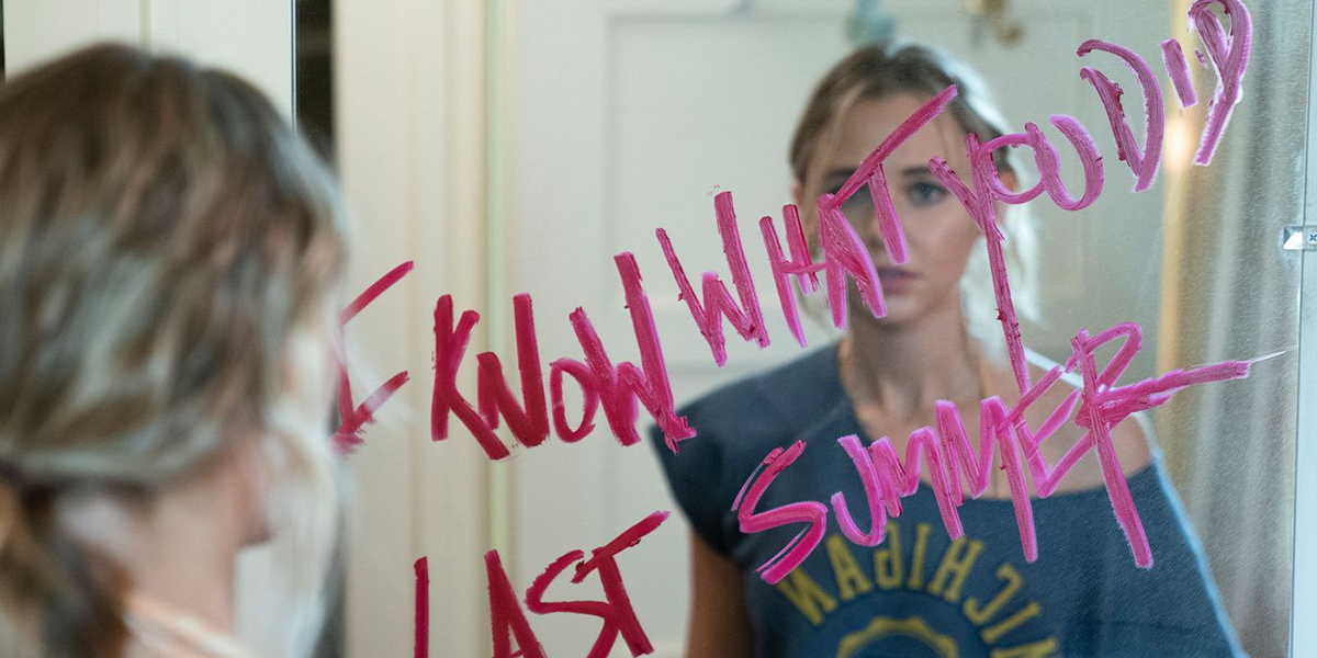 Allison stands in front of a mirror that says I KNOW WHAT YOU DID LAST SUMMER in pink lipstick