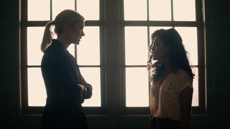 Kate, with her arms crossed, confronts Lucy about discussing their relationship in the office. 