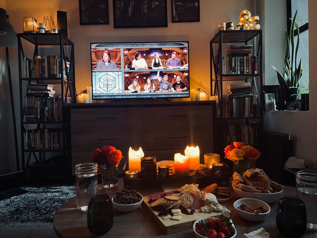 view of the coffee table with half-eaten snacks and critical role playing on the television