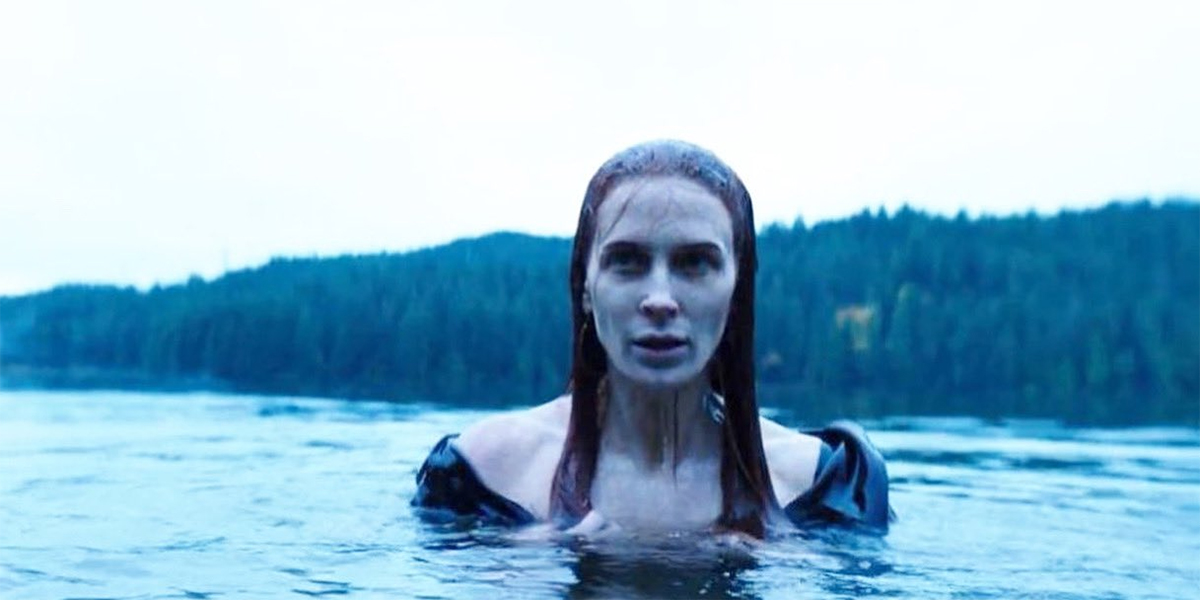 Bridget Regan as Poison Ivy pokes her head out of a lake