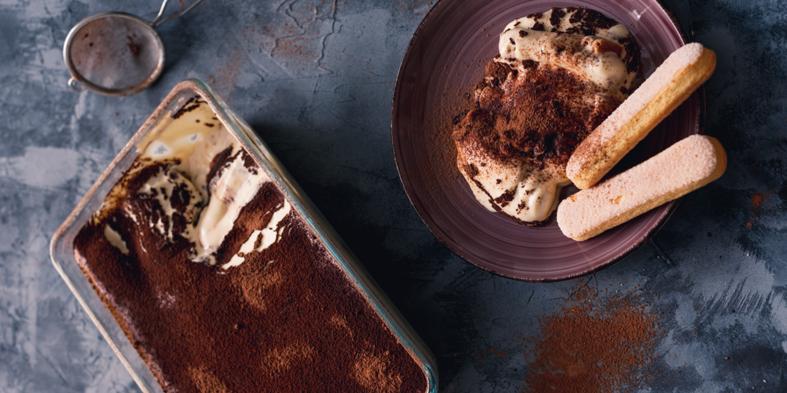 A tin of tiramisu with a piece cut out of it. The piece is sitting on a plate that has two ladyfinger cookies on it.
