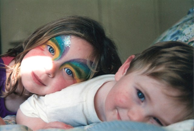 Two children, a girl and a boy, smile while snuggling.