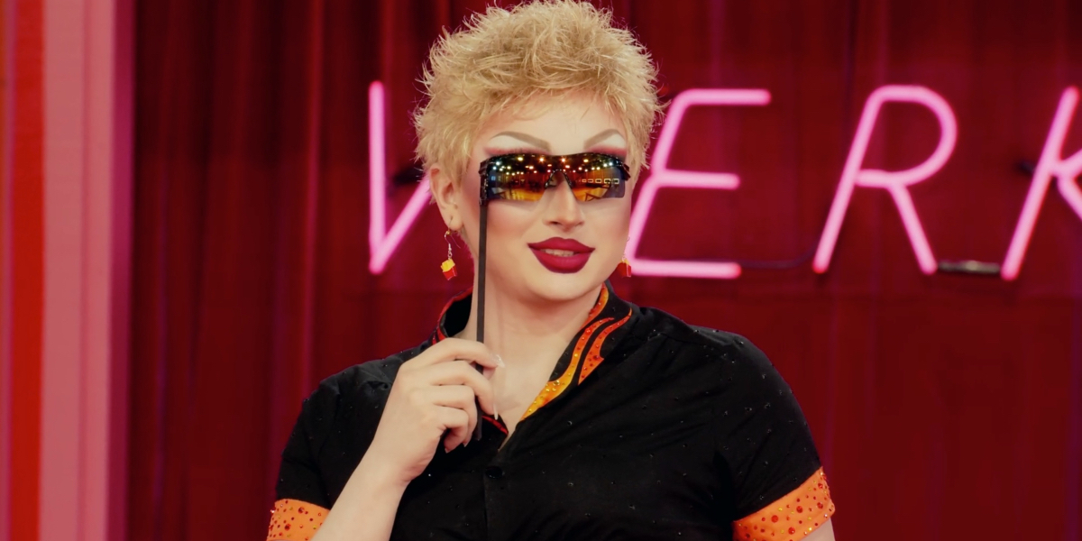 drag race recap 1402: Maddy Morphosis in Guy Fieri drag holds a pair of sunglasses to her face.