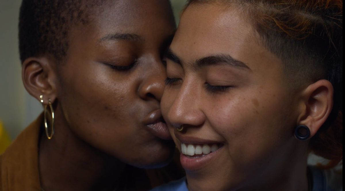 Noor kisses Layla sweetly on the cheek, both of their eyes are closed as Layla has a sweet smile. Queer muslim love