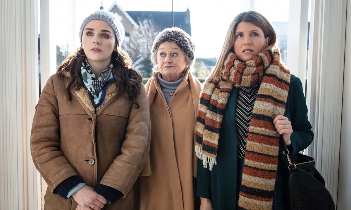 still of three women in winterwear standing in the doorway in "This Way Up"