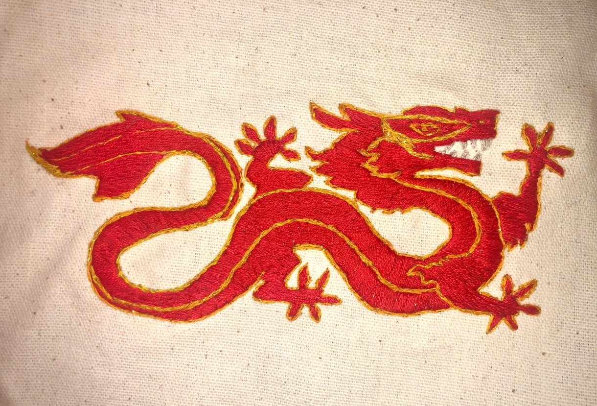 This is a piece of embroidery of a red and gold Asian dragon.