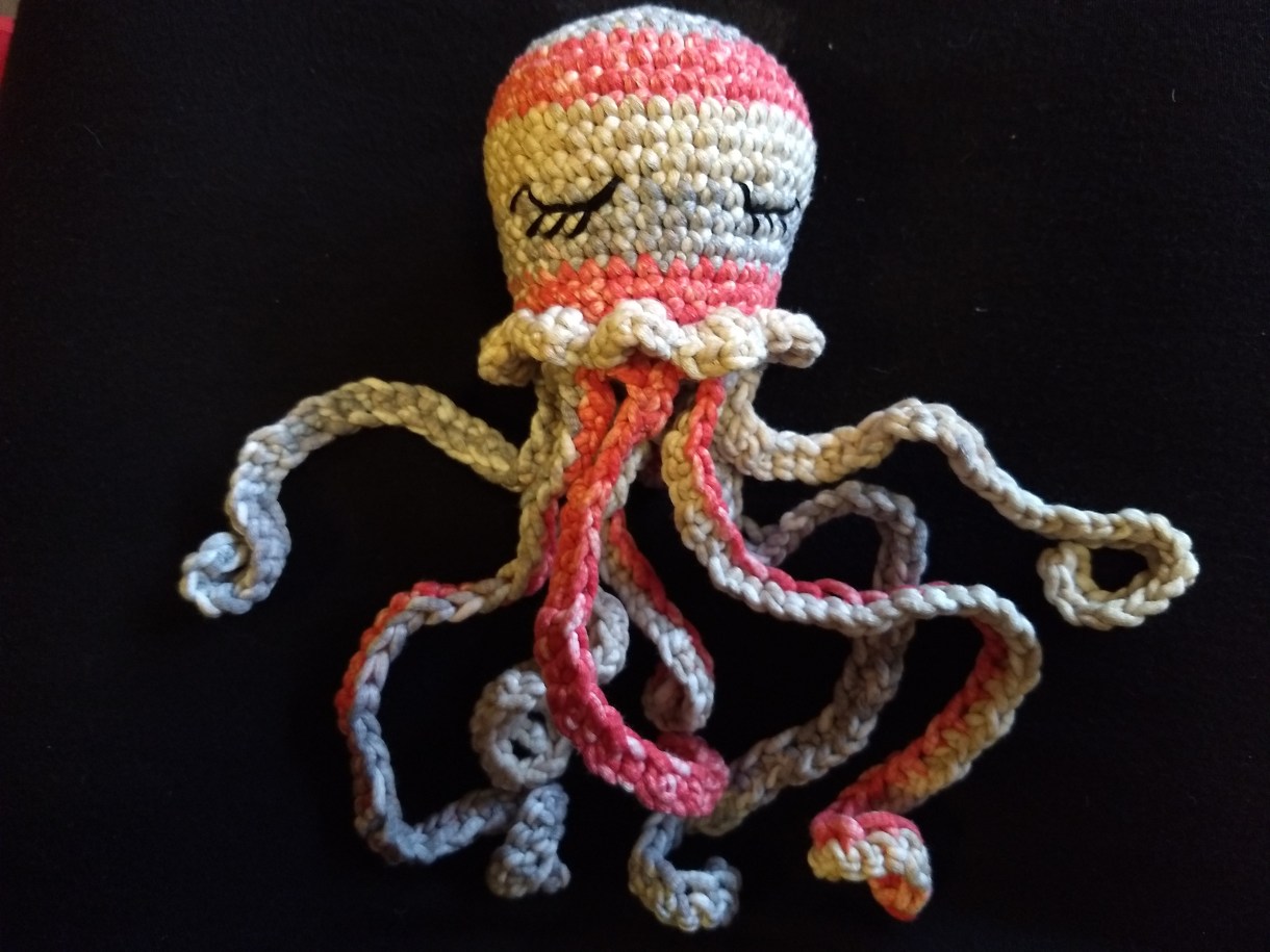 This is a crocheted octopus stretched out to display its long tentacles. It is very cute with cute little eyelashes.