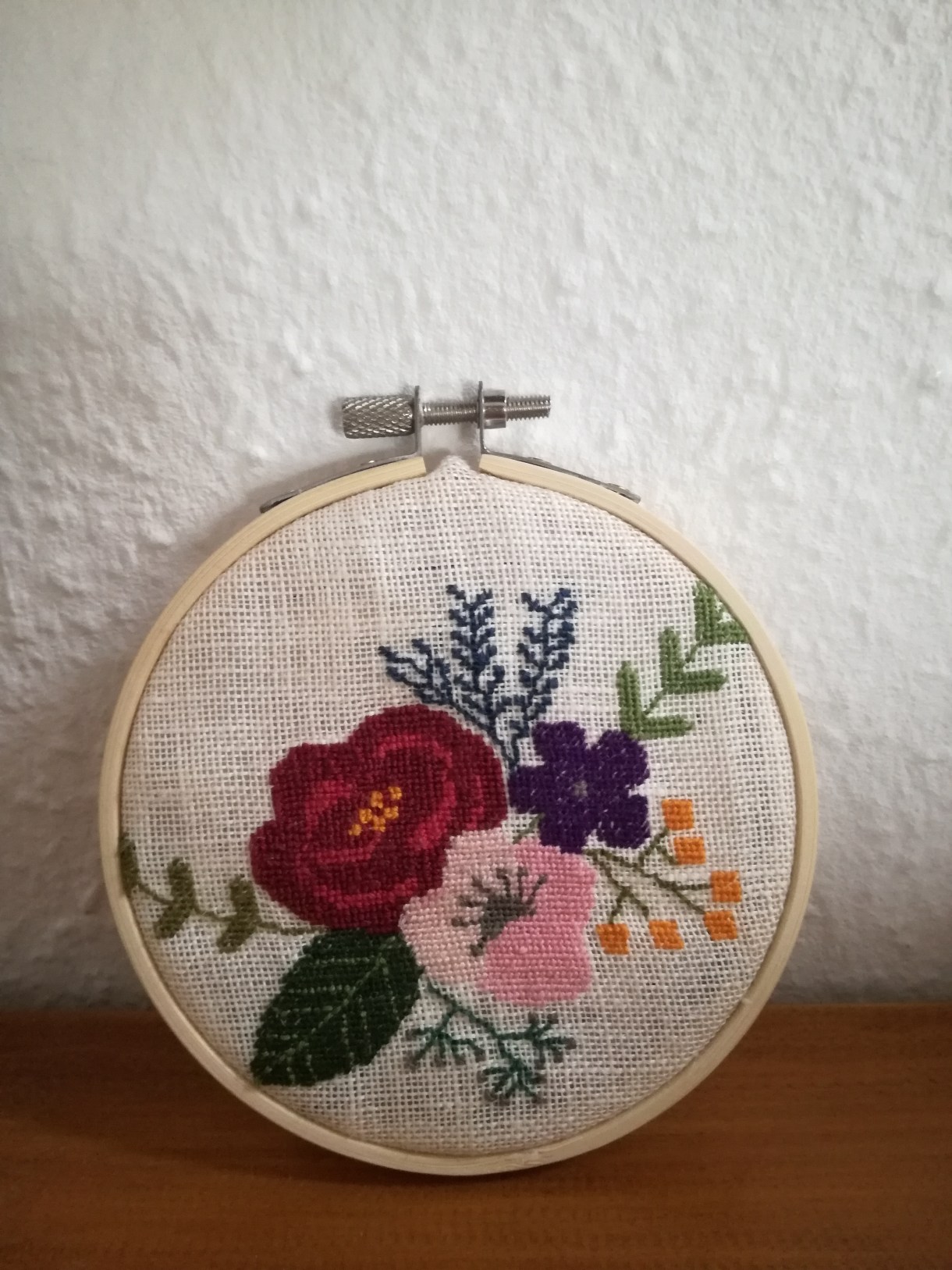 In an embroidery hoop, sits an embroidery of various flowers.