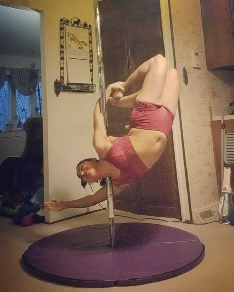 Erin, here, is also upside down on the pole, but with a back bend and holding her feet.