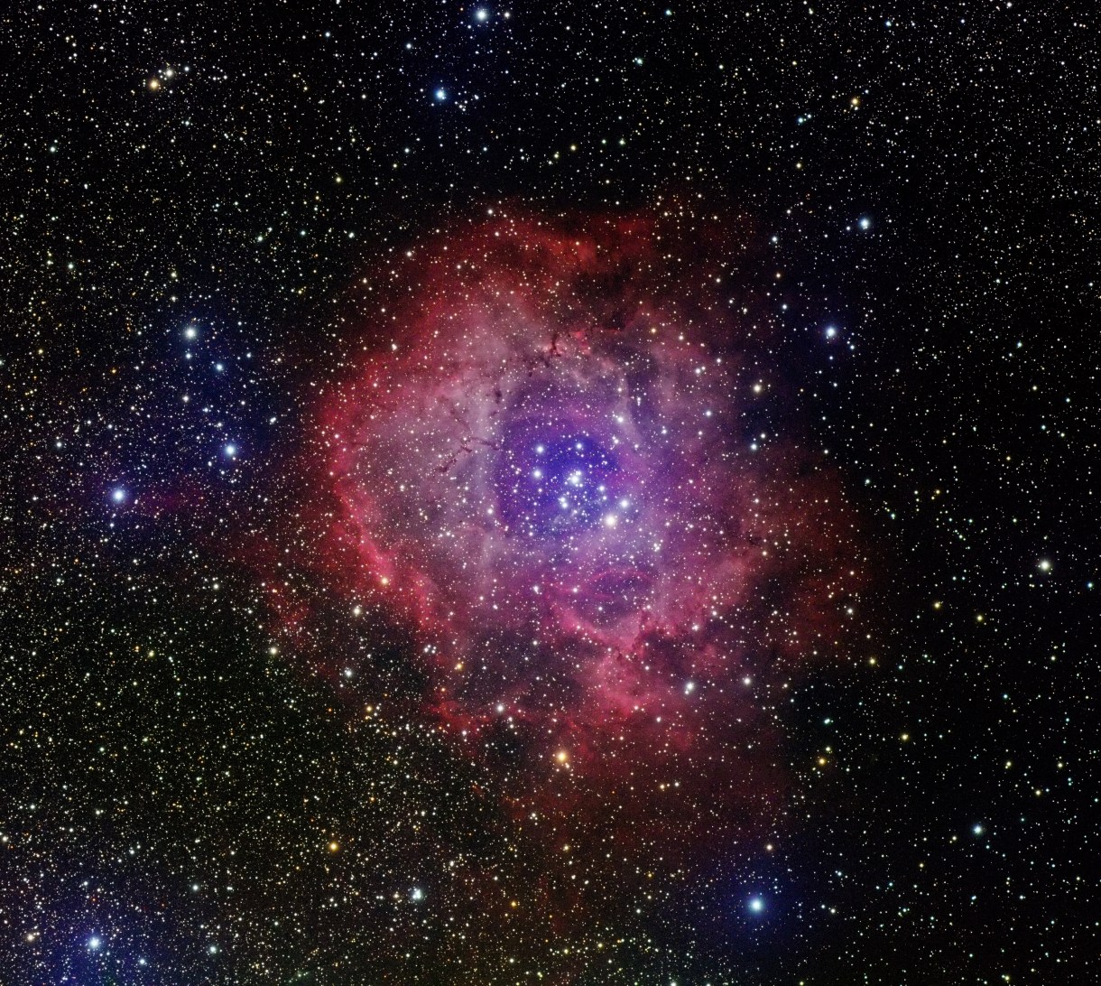 A gorgeous image of outer space. A cloudy red and blue nebula is filled with bright stars.