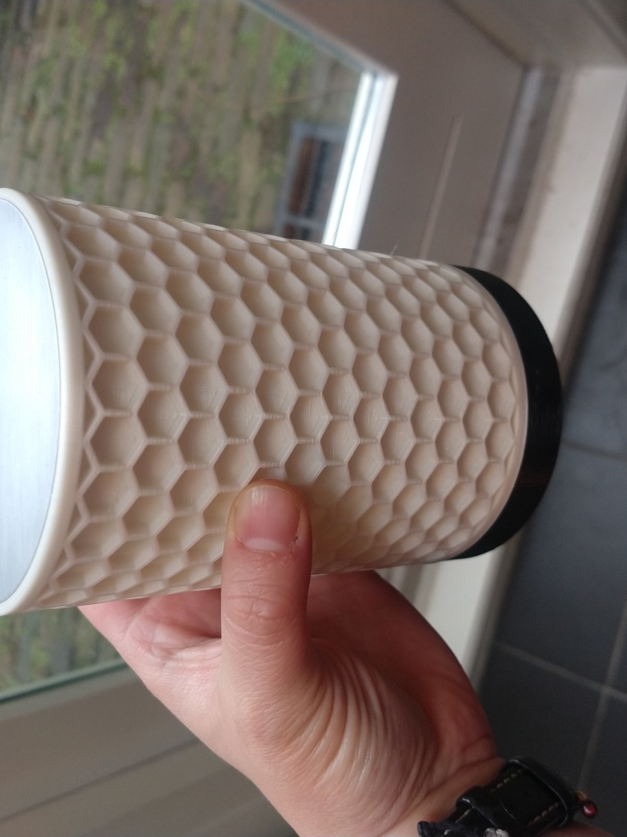 A pale hand holding one of the lamps. It has an off-white honeycomb pattern.