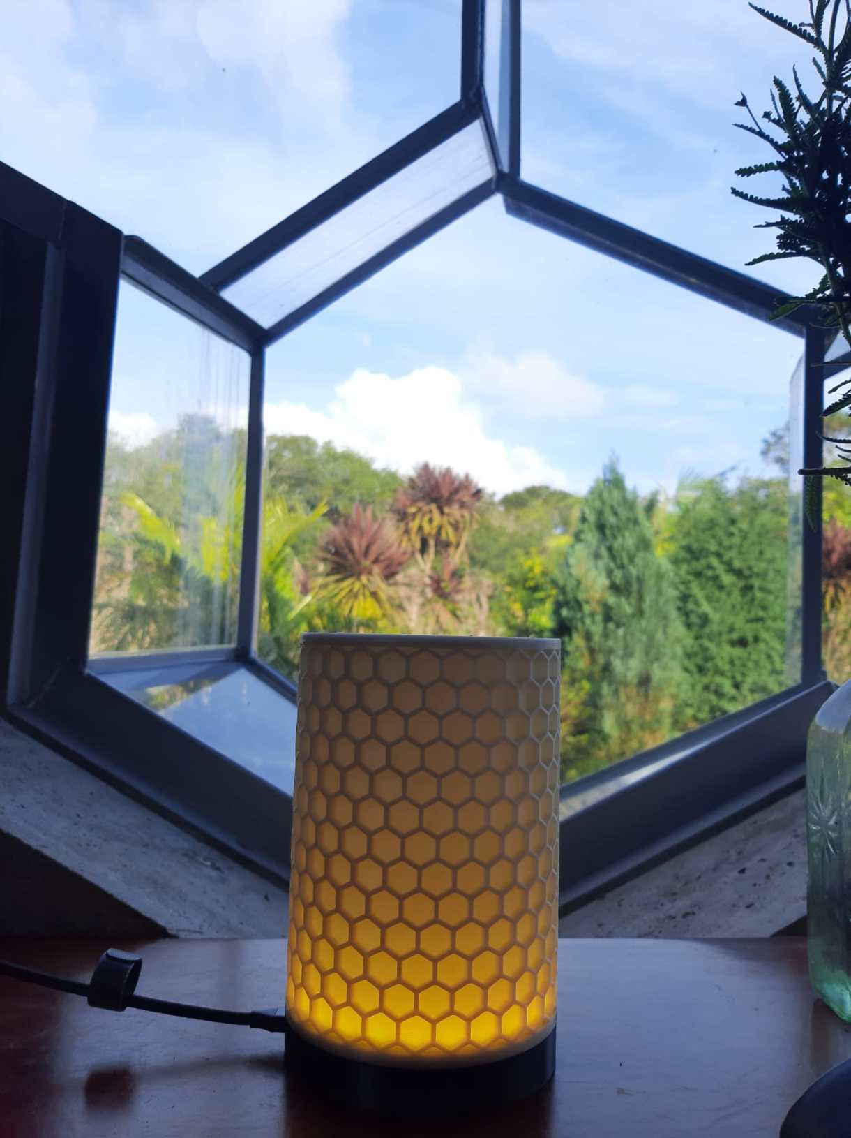 One of the lamps sitting in a honeycomb shaped window, with a soft, yellow glow inside of it.