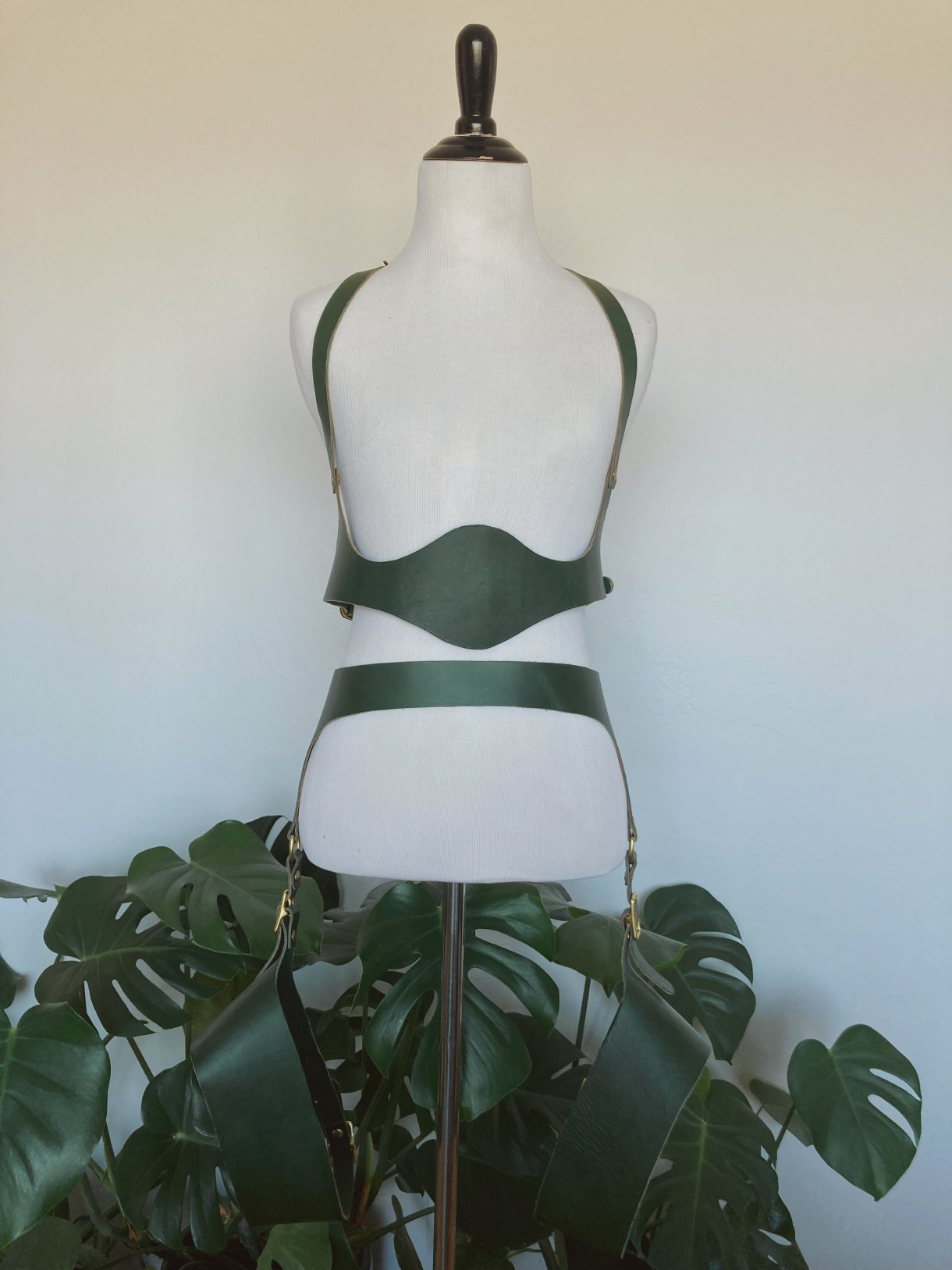 A completed leather harness set on a mannequin. The harness includes a mid-body design, a belt, and what look like thigh straps.