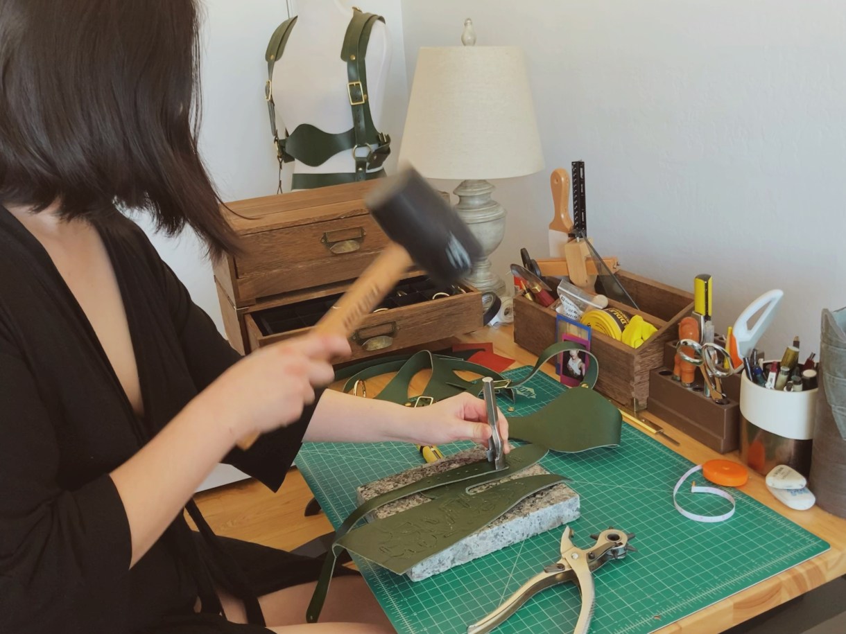 Here is an image of estelle working on some leather with a mallet and metal tool.