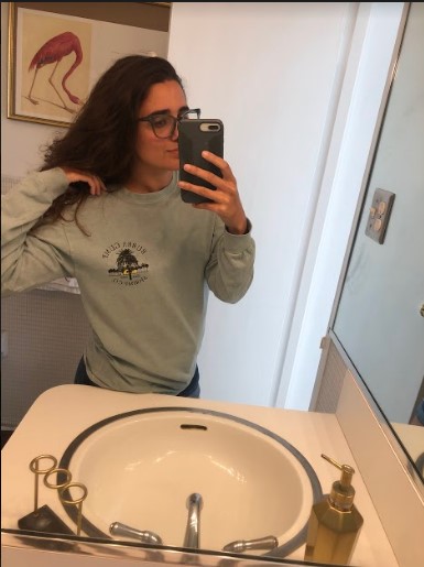 Kayla, a South Asian woman with long brown hair and glasses, is wearing a Bubba Gump long-sleeved tee shirt