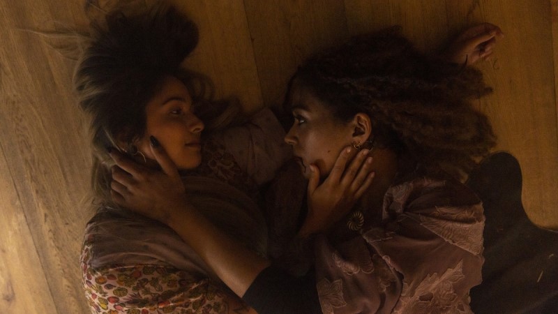 Olivia and Cara lie on the floor and hold each other's faces