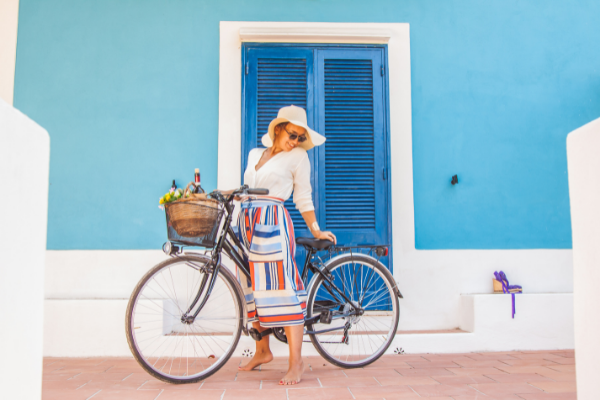 A woman stands near a bicycle in front of a blue-painted set of shuttered doors