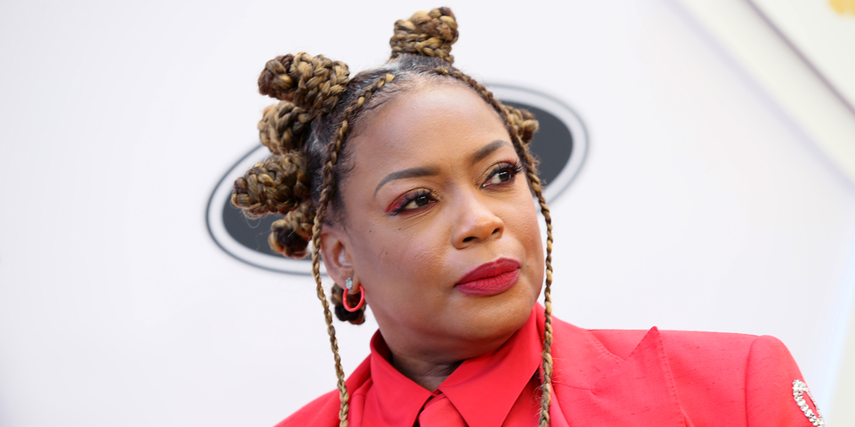 Aunjanue Ellis walks the red carpet for Essence's Black Women in Hollywood. Her hair is braided into bantu knots and her red suit coat is custom bedazzled with the word