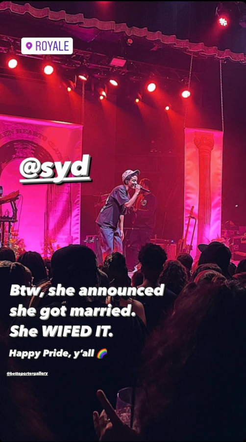 A vertical screenshot of Sad at a concert in Boston, she is on stage in front of a large crowd with red lights behind her. Superimposed on the image is the following test "Syd" / "Btw, she announced she got married. She WIFED it. Happy pride, y'all"