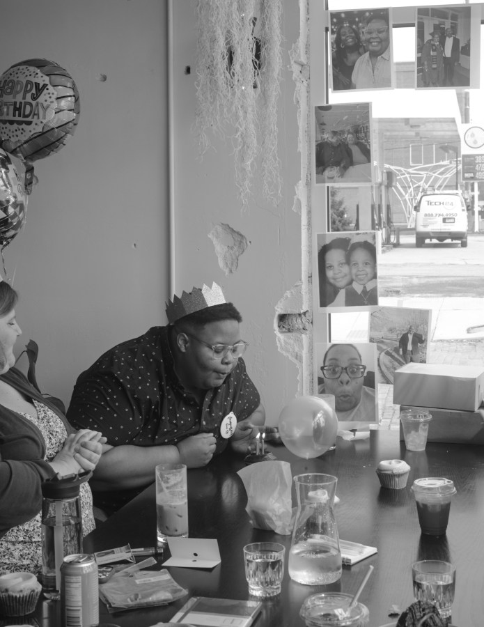 shea, in a crown, blows out birthday candles at the coffeeshop