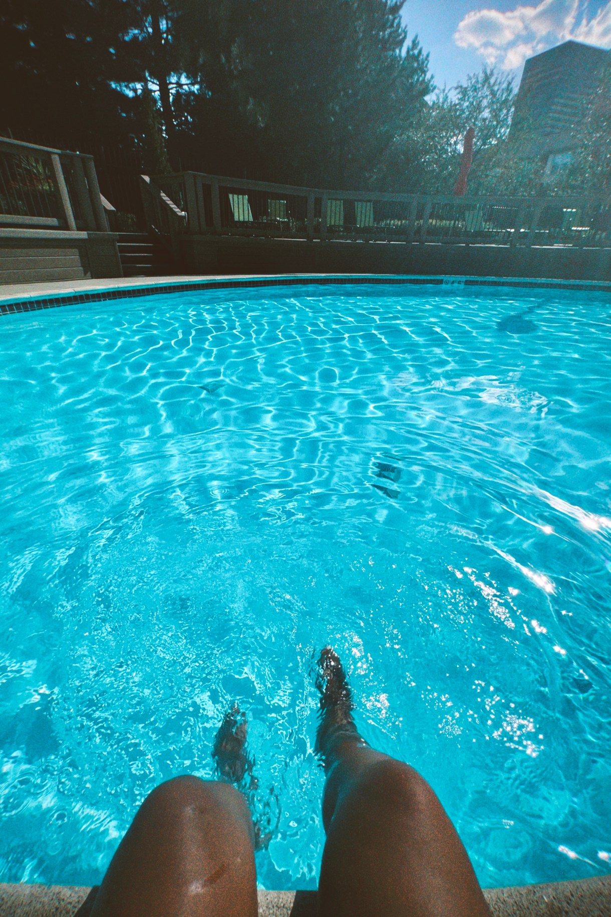 a photo taken from Carmen's perspective of her legs splashing in a pool