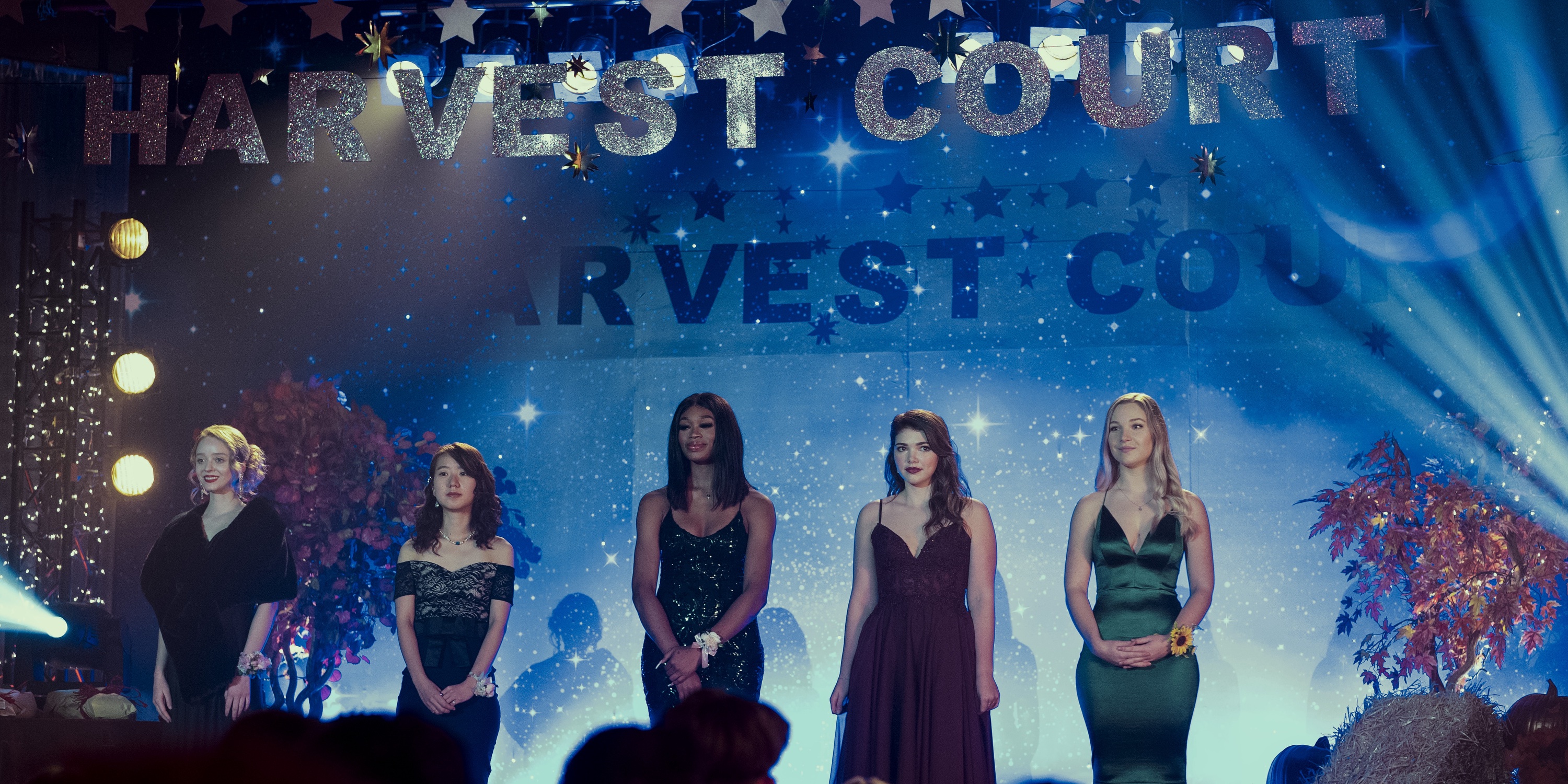 teenage girls competing for Harvest Court stand on the stage in gowns