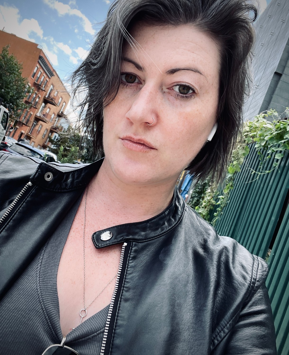 meg, a white woman with dark salt and pepper hair looks at the camera. she is wearing a leather jacket and a gray tee shirt