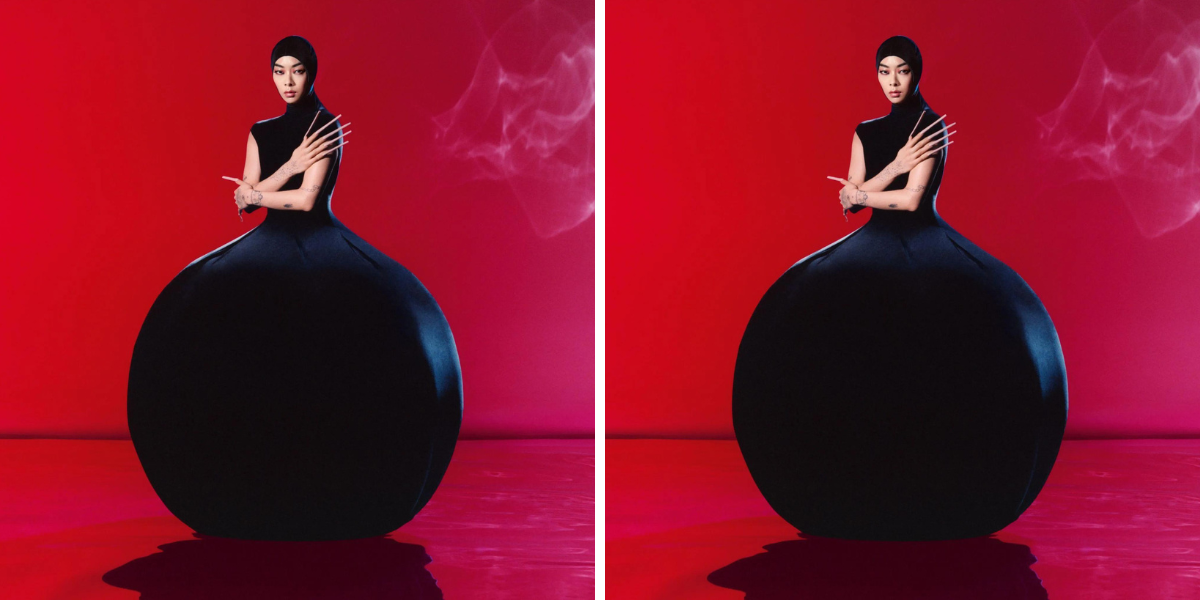 Sawayama in a large black gown that billows out into a ball shape against a red background.