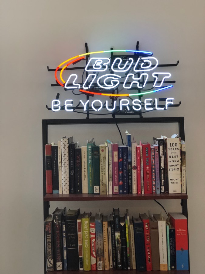 A rainbow Bud Light neon sign that says BE YOURSELF