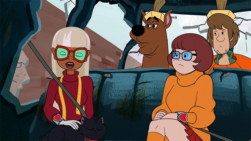 Coco and Velma sit beside each other in the Mystery Machine