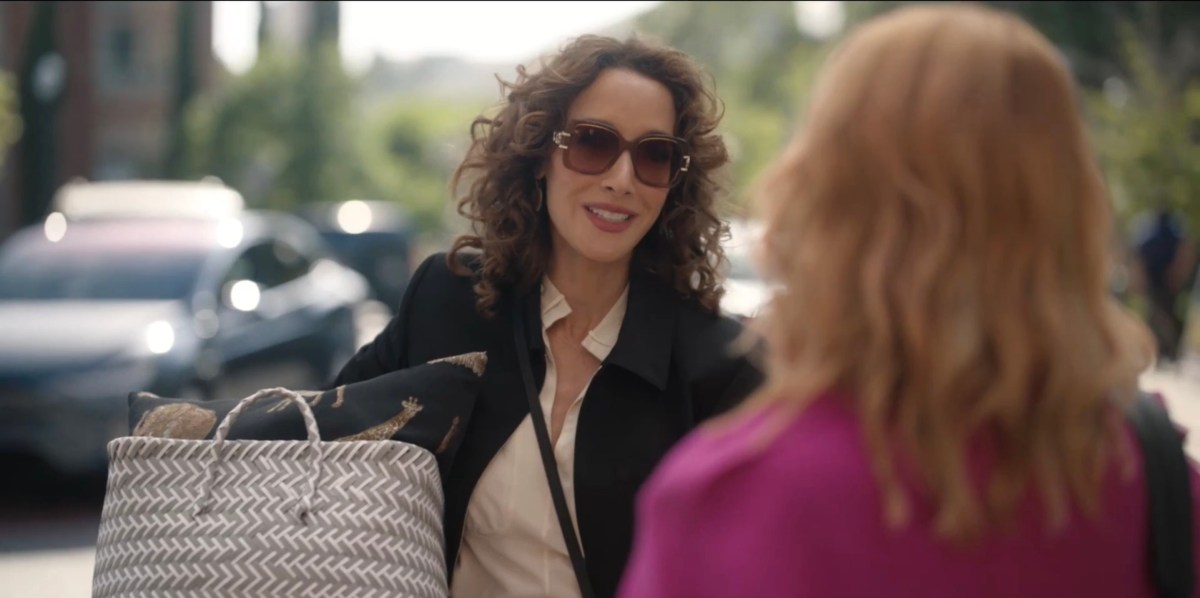 Bette porter holding a basket of goods talking to Tina