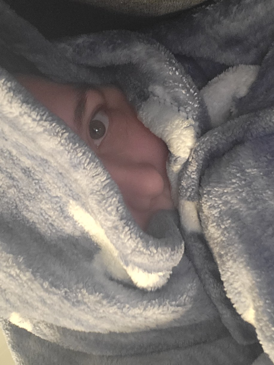 Valerie, a white woman, peeks out from a blanket wrapped around head and upper body