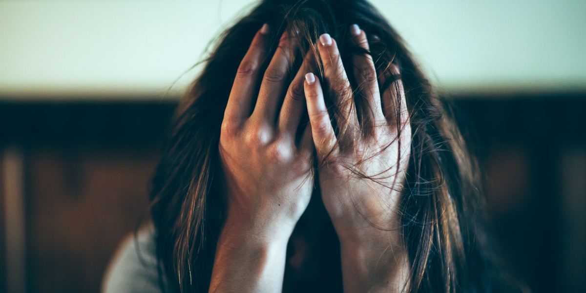 A woman covers her face in anxiety