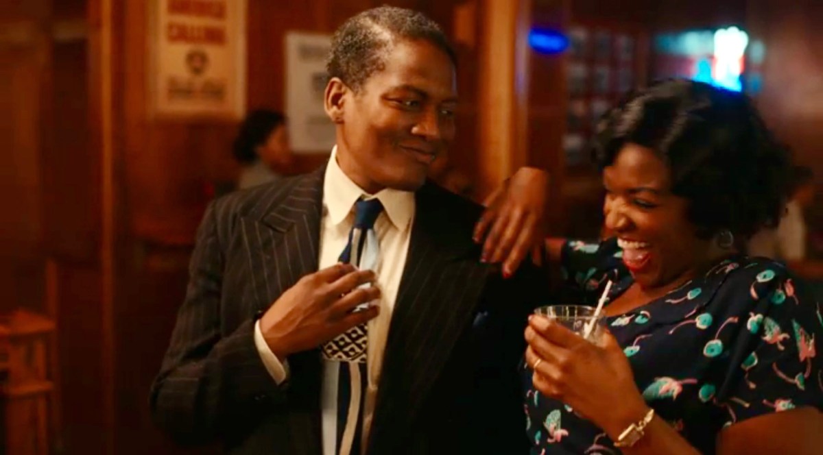 Bertie adjusts his tie while Grace smiles at him