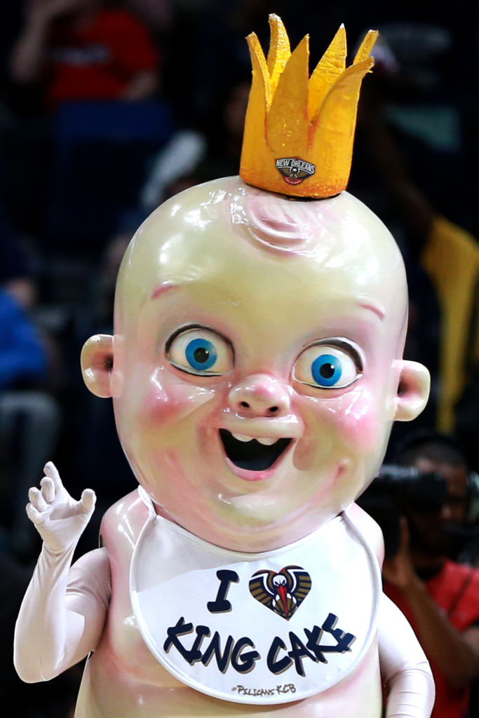 a ghastly baby mascot with a crown and a bib that says "I heart king cake"