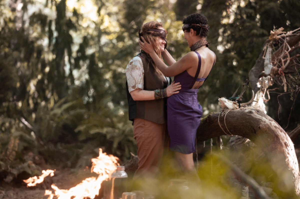 Van and Taissa embrace in the Yellowjackets episode "Doomcoming", wearing masks and bachanal like outfits