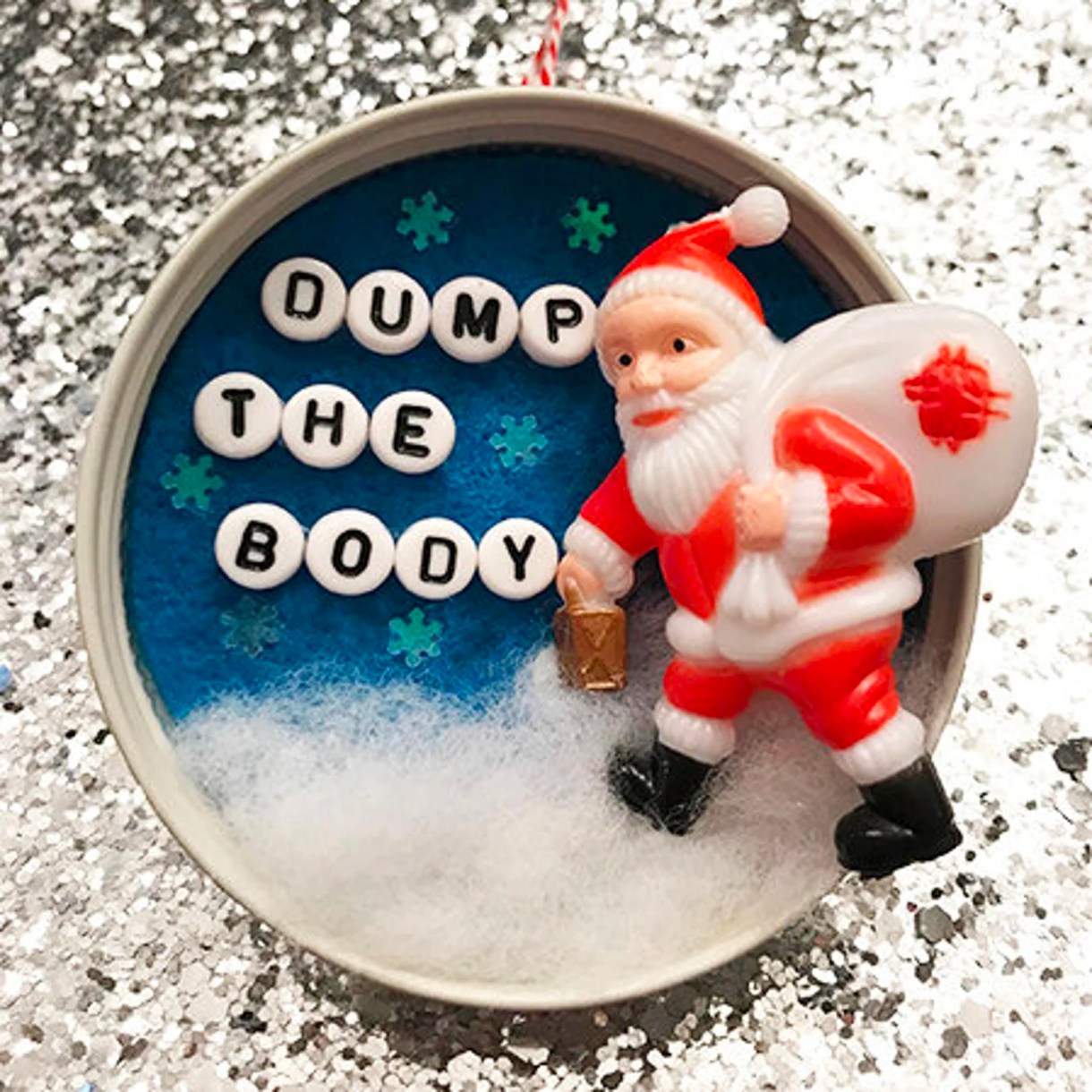 a santa ornament where the white toy sack on santa has a red stain on it and lettering on the ornament reads "dump the body"