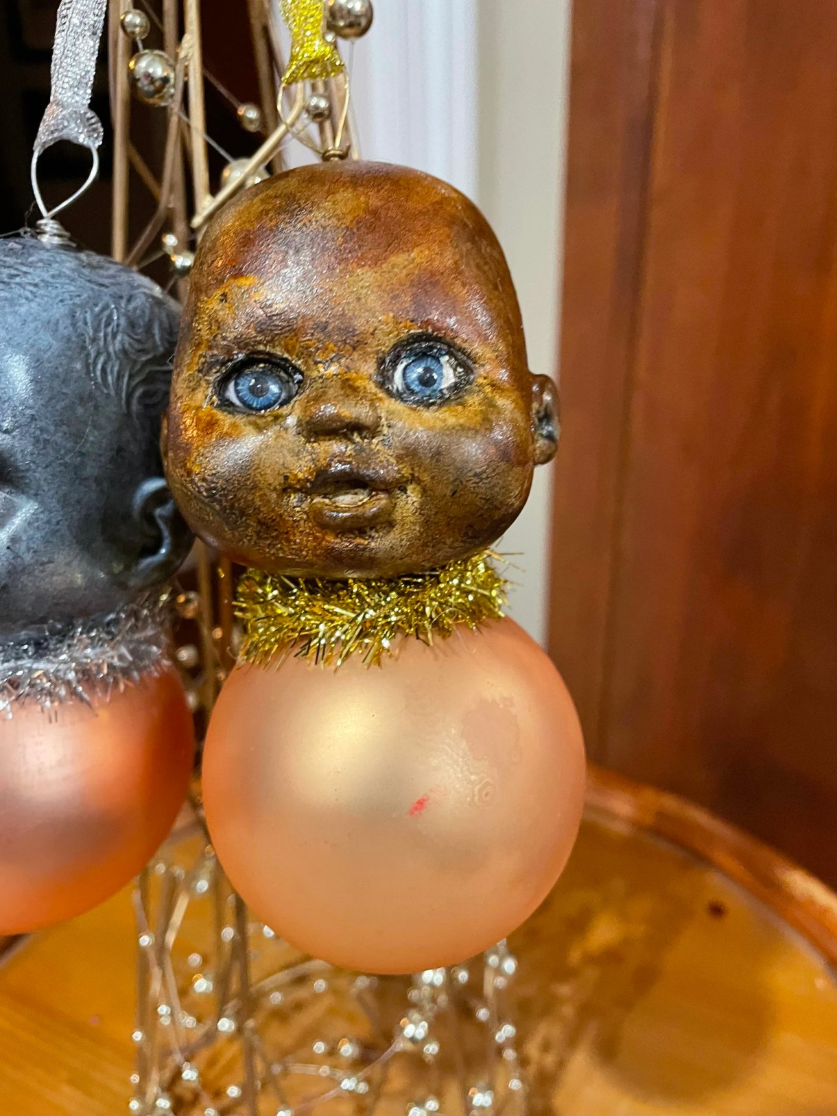 an ornament made from a baby head that has been painted inexplicably bronze