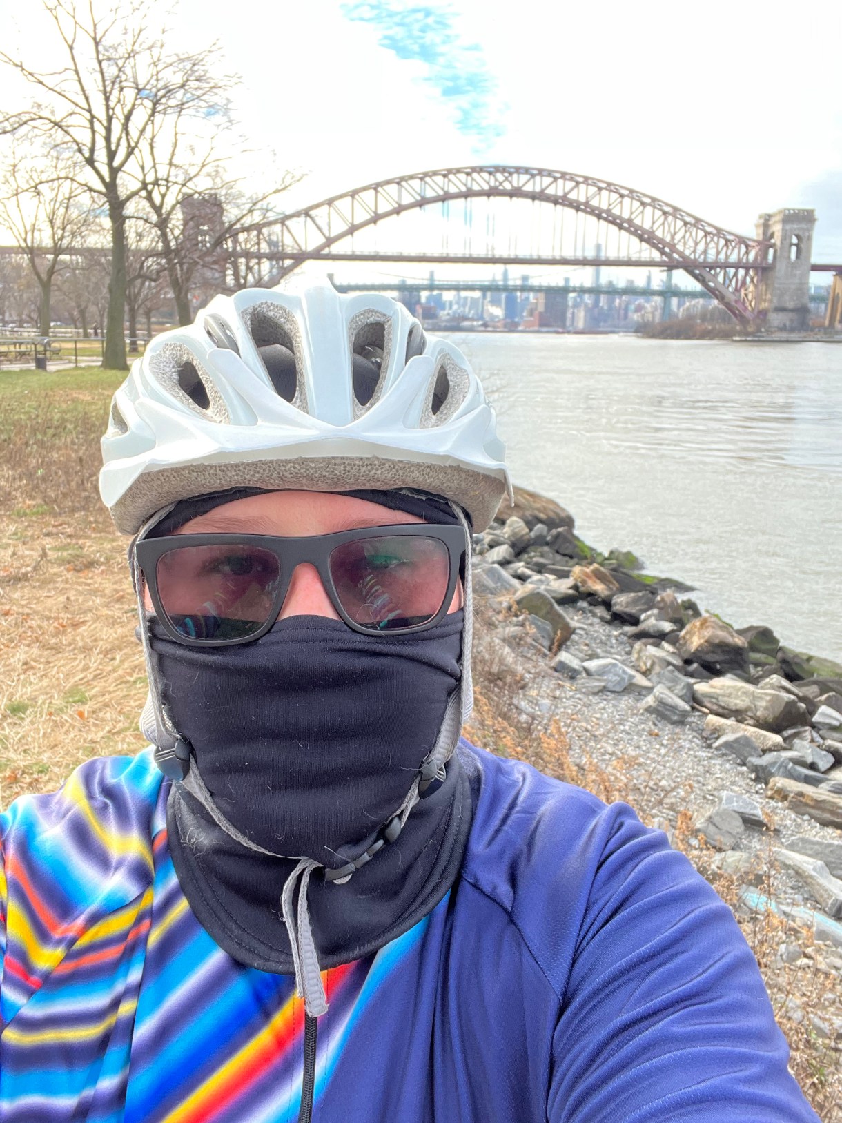 heather a soft butch white woman with glasses wears a bike riding outfit, face covering and helmet and rides her bike outside in NYC