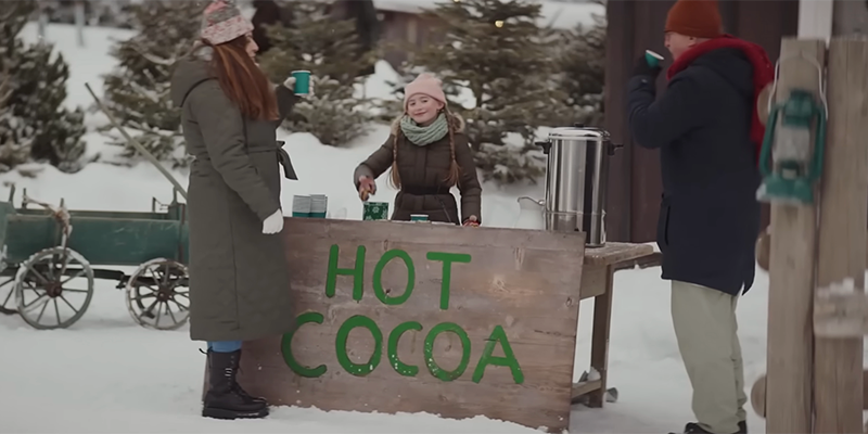 little girl with "Hot Cocoa" sign