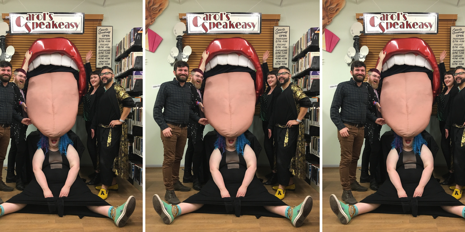 This image features a giant 3D tongue art installation that used to hang at Carol's Speakeasy. The lips are red and shiny, the teeth are large and white, and the tongue is pink and sticking out of the mouth. Five queer volunteers at the archive pose around the tongue, smiling and laughing with this piece of queer history.