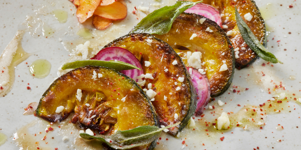 Roasted kabocha squash on a plate with cheese, beets, and greens